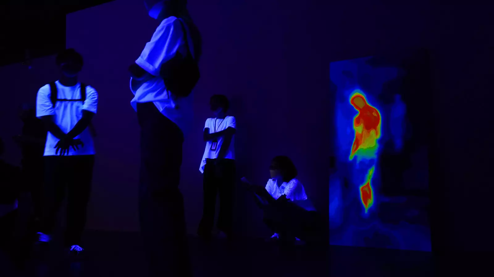 以熱感應器成像作為基礎的畫作，以及展場中被紫外線燈光照射下的觀者｜圖片提供：臺北數位藝術中心。